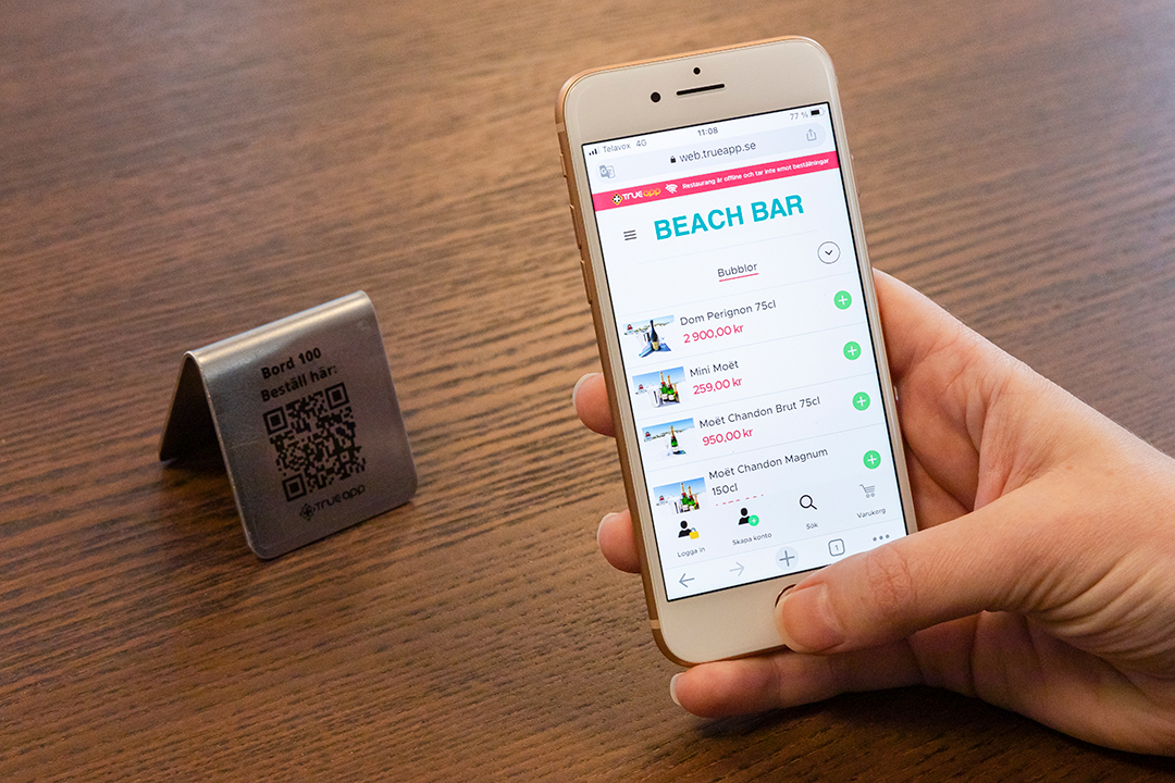 TrueAPP på en mobil som en person håller i.