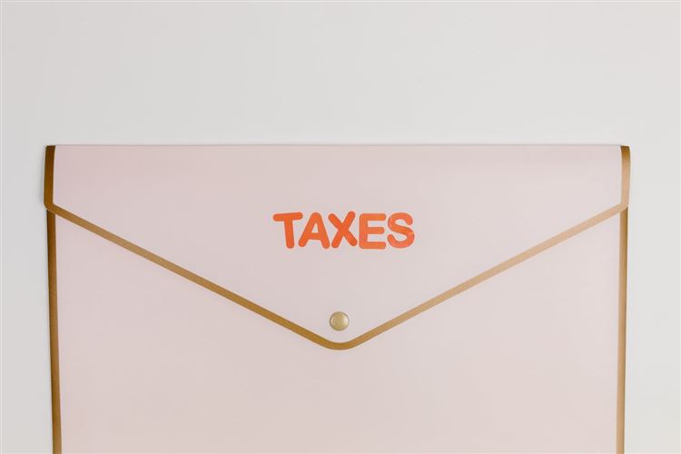 En mapp av papp där det står "taxes" på för att symbolisera F-skattsedel.